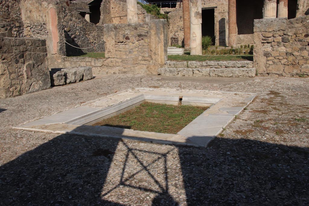 VII.7.5 Pompeii. October 2023. 
Looking north-west across impluvium in atrium towards west ala (e ), on left. Photo courtesy of Klaus Heese.
