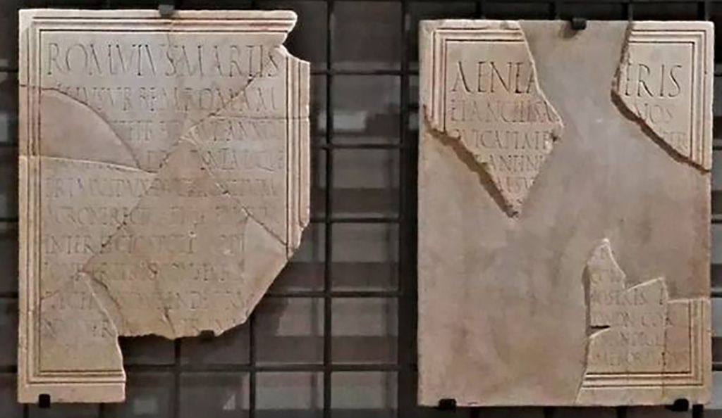 VII.9.1 Pompeii. June 2017. Marble dedication plaques to Romulus (left) and Aeneas (right) found near the so-called Building of Eumachia in 1817.
Now in Naples Archaeological Museum. Inventory numbers 3820 (Romulus) and 3819 (Aeneas).
Photo (detail) courtesy of Giuseppe Ciaramella. 
