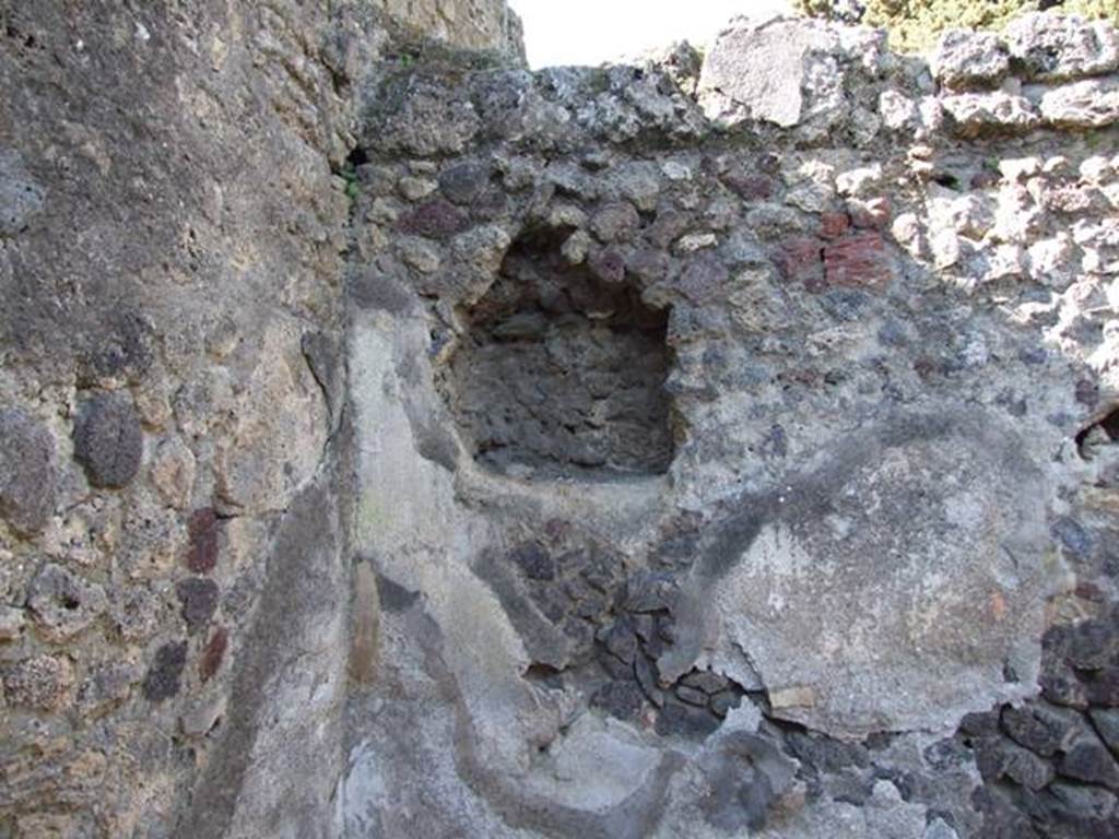 IX.9.12 Pompeii. March 2009. Room 15, remains of niche in north-west corner of kitchen
According to NdS, on the extreme west of the north wall of the kitchen was a rectangular niche, protected by a small roof.
Near this was found the usual painted lararium with Lares, the family Genius sacrificing at the altar, and a tibicin with double flute.
See Notizie degli Scavi di Antichità, 1891, (p.256).
According to Boyce –
In the north wall of the kitchen is a square niche (0.65 square, d.0.25, h. above floor 1.50), with a projecting tile below.
On the wall to the right of it are visible traces of a lararium painting: in the centre, the Genius (h.0.48) with a fold of the toga drawn over his head pours a libation from a patera upon an altar; behind him is the tibicen (h.0.38); on each side stands a Lar (h.0.67) in short tunic, a wreath of leaves upon his head, carrying rhyton and patera.
See Boyce G. K., 1937. Corpus of the Lararia of Pompeii. Rome: MAAR 14. (p.93, no.465).

