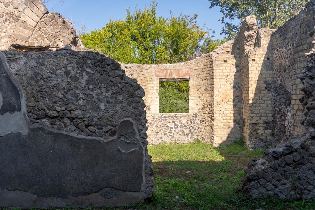 Villa of Mysteries, Pompeii. October 2023. 
Room 26, at front, looking into room 25, apsidal hall at rear. Photo courtesy of Johannes Eber.
According to Boyce –
In a room opening off the north-west corner of large peristyle is a room of curious shape with an apse in the side opposite the entrance door, and four rectangular niches in the walls. It was undergoing renovation at the time of the eruption designed to make it a finer room that before. 
Maiuri thought it may have been intended as a domestic Sacellum, and possibly would have housed the statue of Livia found nearby in the peristyle.
See Boyce G. K., 1937. Corpus of the Lararia of Pompeii. Rome: MAAR 14. (p. 98, no. 484). 
See Maiuri, 1967 Ed. Villa dei Misteri, (76 and fig.29)
