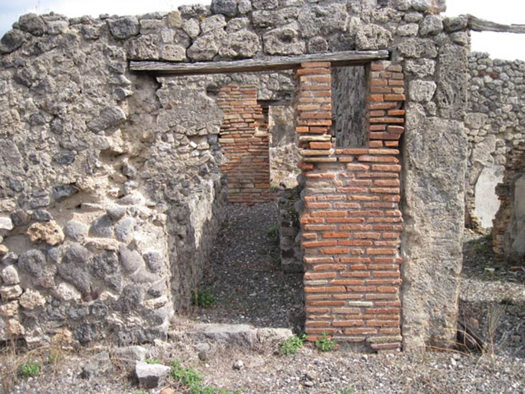 I.3.8b Pompeii. September 2010. Looking east towards south-central doorway from east portico of peristyle, towards kitchen at rear. Photo courtesy of Drew Baker.
According to Boyce, somewhere along the east wall of the peristyle was a niche.
In the niche, a terracotta statuette of Minerva was found. She was wearing a helmet and holding a shield on her left arm, and holding a patera in her right hand.
See Boyce G. K., 1937. Corpus of the Lararia of Pompeii. Rome: MAAR 14. (p.24, no.22)
Giorn.Scavi, N.S., i, 1869, 301.
Boyce gave a note 1 on page 24, to this entry . It read –
In a room opening off the east side of the peristyle a bronze statuette of Fortuna was found. She was holding a cornucopia against her left shoulder.
Giorn. Scavi, N.S., i, 1869, 305. 

