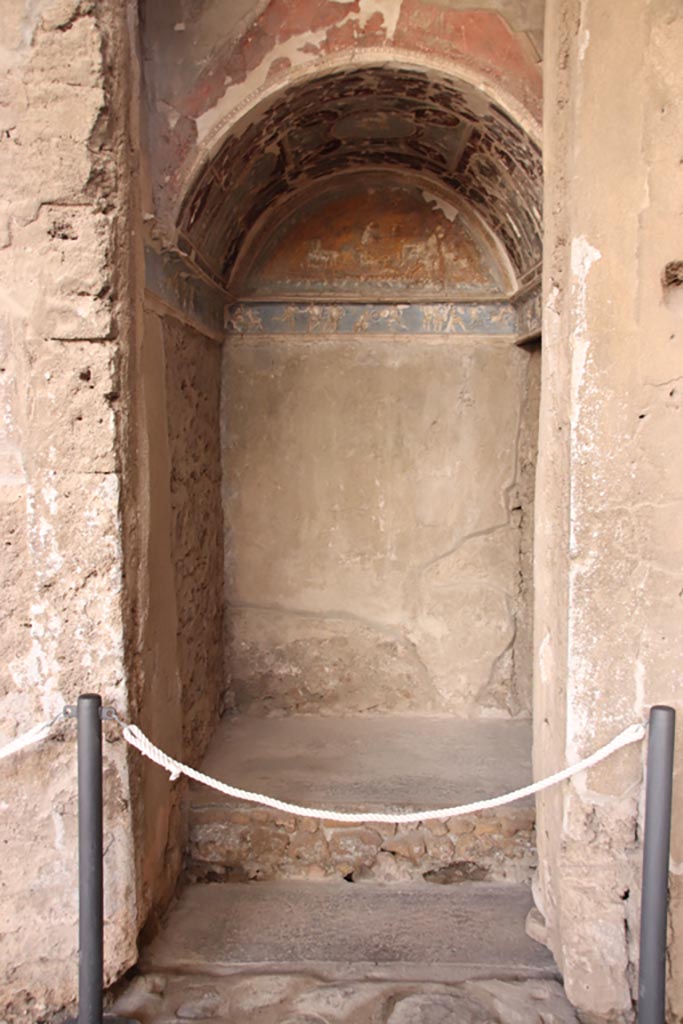 I.6.4 Pompeii. October 2022. 
Room 16, looking south into sacellum in south-west corner of atrium. Photo courtesy of Klaus Heese. 
According to Boyce –
On the right of the tablinum is a recess with vaulted ceiling and a figures frieze running around three walls.
This frieze depicts scenes from the Iliad with figures in white stucco relief upon a ground of blue.
It has been suggested, without very good reason, that this room was the lararium.
He quoted Not. Scavi, 1913, 28.
See Boyce G. K., 1937. Corpus of the Lararia of Pompeii. Rome: MAAR 14. (p.25, no.37).

