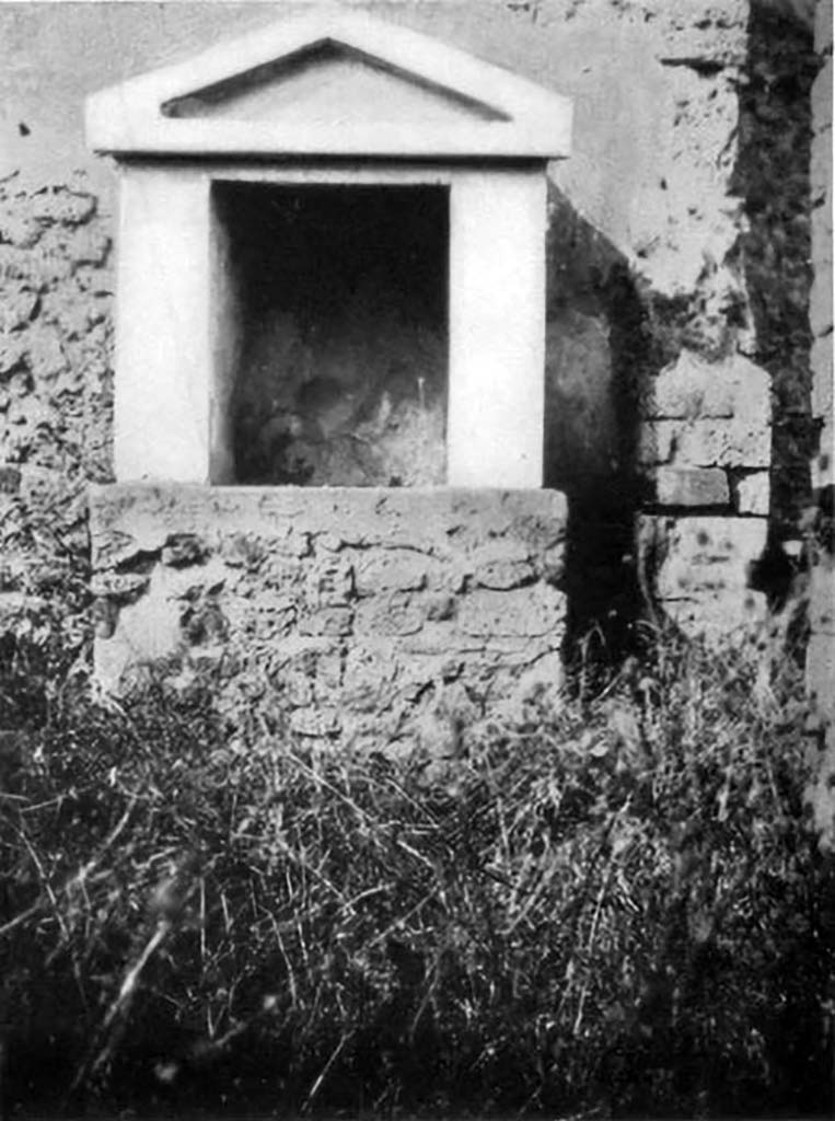 VI.5.14 Pompeii. 1930s photo of lararium by Tatiana Warscher.
According to Boyce, it had a solid base with two heavy walls forming a rectangular niche, surmounted by a gable roof with a simple pediment.
The walls inside were covered with unpainted white stucco.
In the floor was embedded a square block of marble, in which was cut a rectangular hole.
It was as if this was meant to hold the pivot upon which turned a door to close the shrine.
See Boyce G. K., 1937. Corpus of the Lararia of Pompeii. Rome: MAAR 14.  (p.46, no.154, and Pl.34,2)
See Giacobello, F., 2008. Larari Pompeiani: Iconografia e culto dei Lari in ambito domestico. Milano: LED Edizioni. (p.269)
