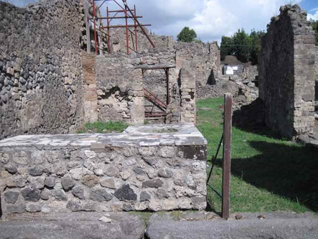 1.2.1 Pompeii. September 2010. Entrance doorway, looking east.
Photo courtesy of Drew Baker. According to Garcia y Garcia, the joined properties at I.2.1, 30, 31 and 32 suffered from the bombing during the night of 14-15th September 1943. The counter was destroyed and has been wrongly reconstructed with only one of the two dolia. The same bomb fell near entrance number I.2.30, completely destroying the latrine. The south perimeter wall fell down, which has been restored in part. See Garcia y Garcia, L., 2006. Danni di guerra a Pompei. Rome: L’Erma di Bretschneider. (p.37)
