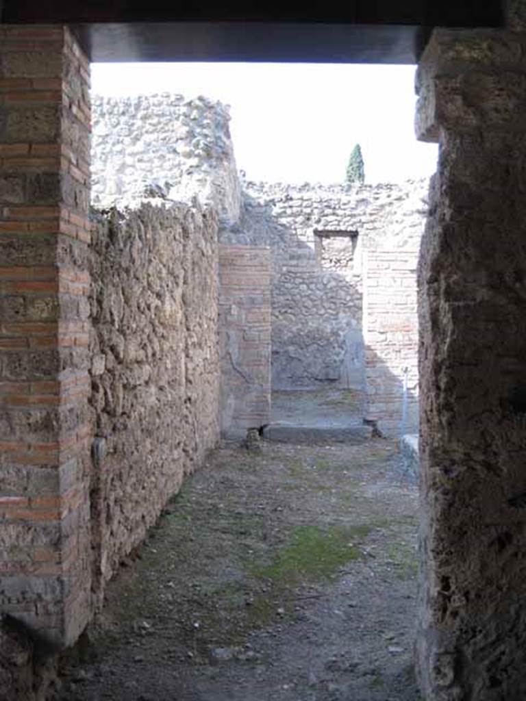 I.5.2 Pompeii. September 2010. Doorway into two rooms at north end of eastern portico looking north. The remains of the solid podium, part of the lararium, can be seen in the lower left. Photo courtesy of Drew Baker.

