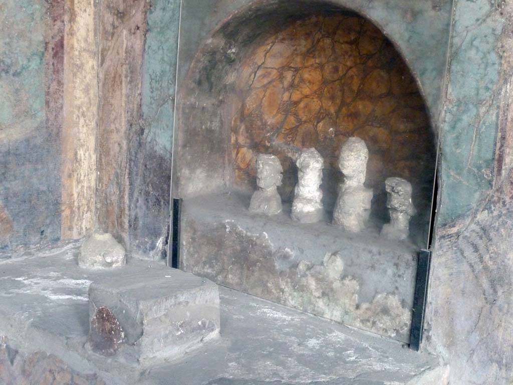 I.10.4 Pompeii. May 2010. 
Alcove 25, lararium or domestic shrine. The busts are plaster cast taken from the cavities left by the original wooden busts. 
