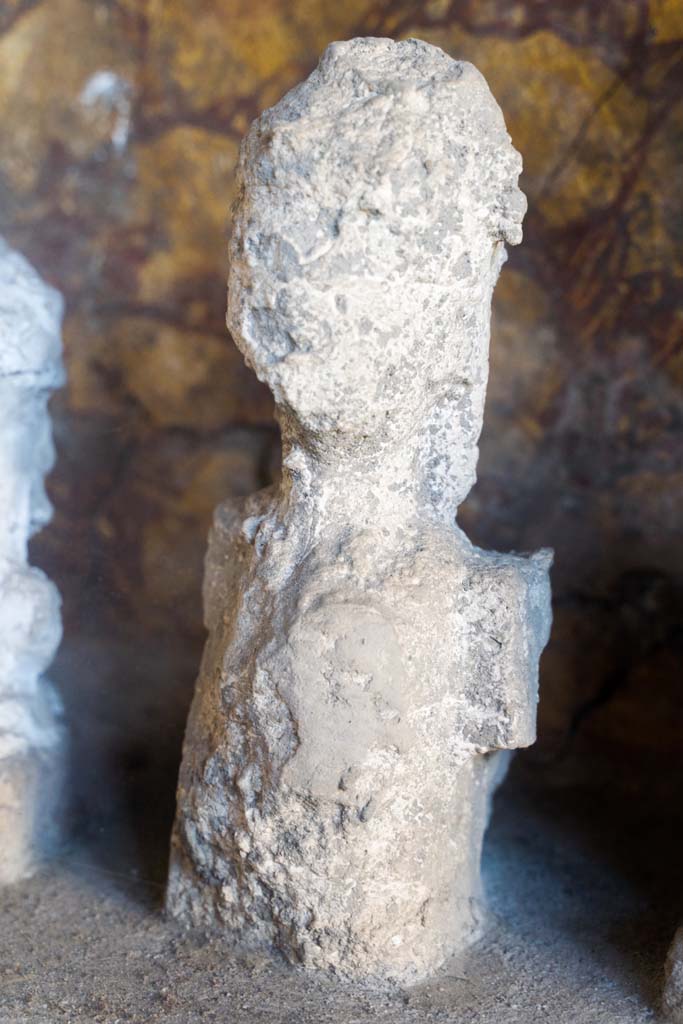 I.10.4 Pompeii. April 2022. 
Alcove 25, detail of plaster cast, seen on the right of centre, on the lararium or domestic shrine. (Image 2).
Photo courtesy of Johannes Eber.
