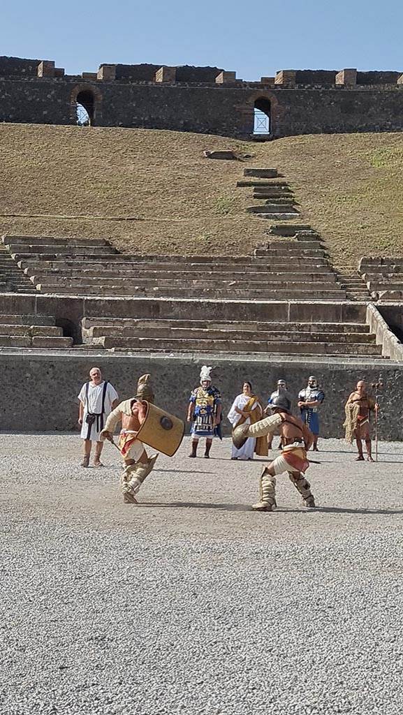 II.6 Pompeii. September 2024. 
Gladiators in combat rehearsing in amphitheatre.  
Photo courtesy of Giuseppe Ciaramella.

