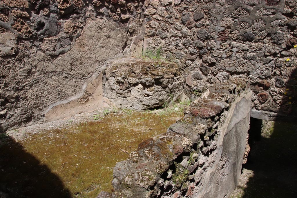 V.1.7 Pompeii. May 2024. 
Room “i”, pedestal on east side of storeroom, with ramp to cellars below room “f”, on right. Photo courtesy of Klaus Heese.
