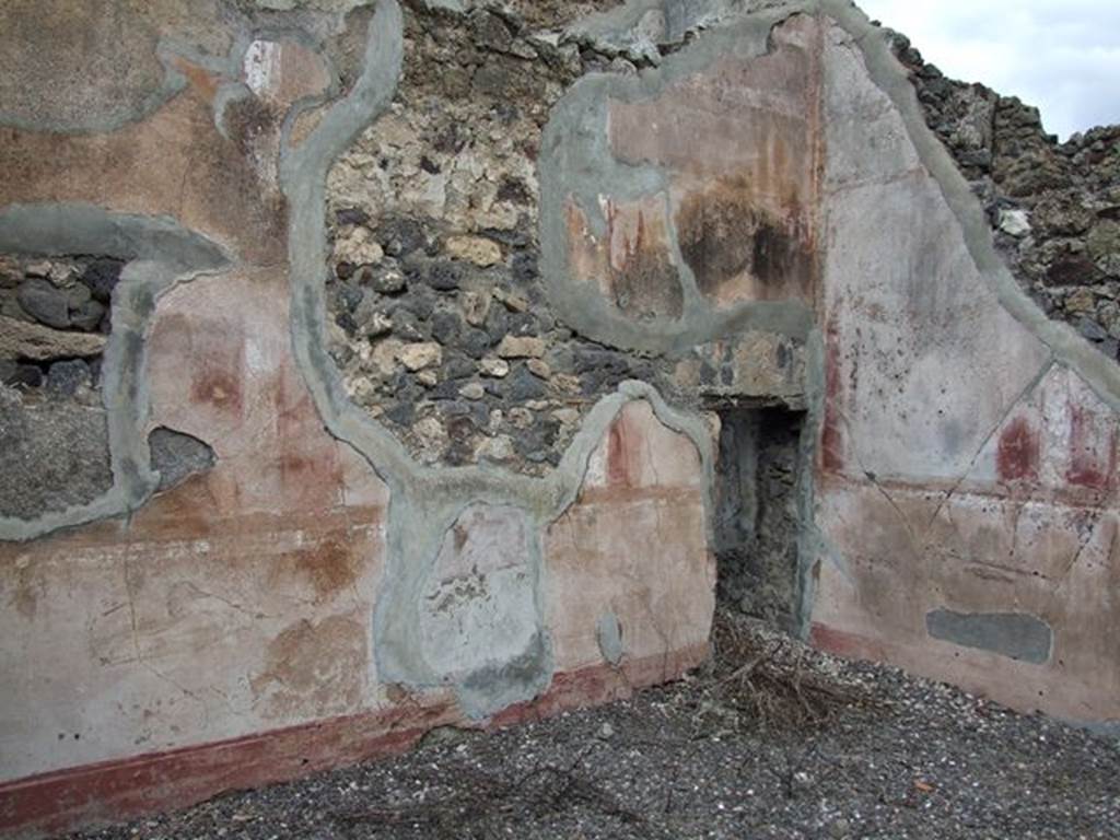 VI.7.19 Pompeii. December 2006. Detail of remains of painted plaster in north-east corner of oecus, with doorway into area below stairs.


