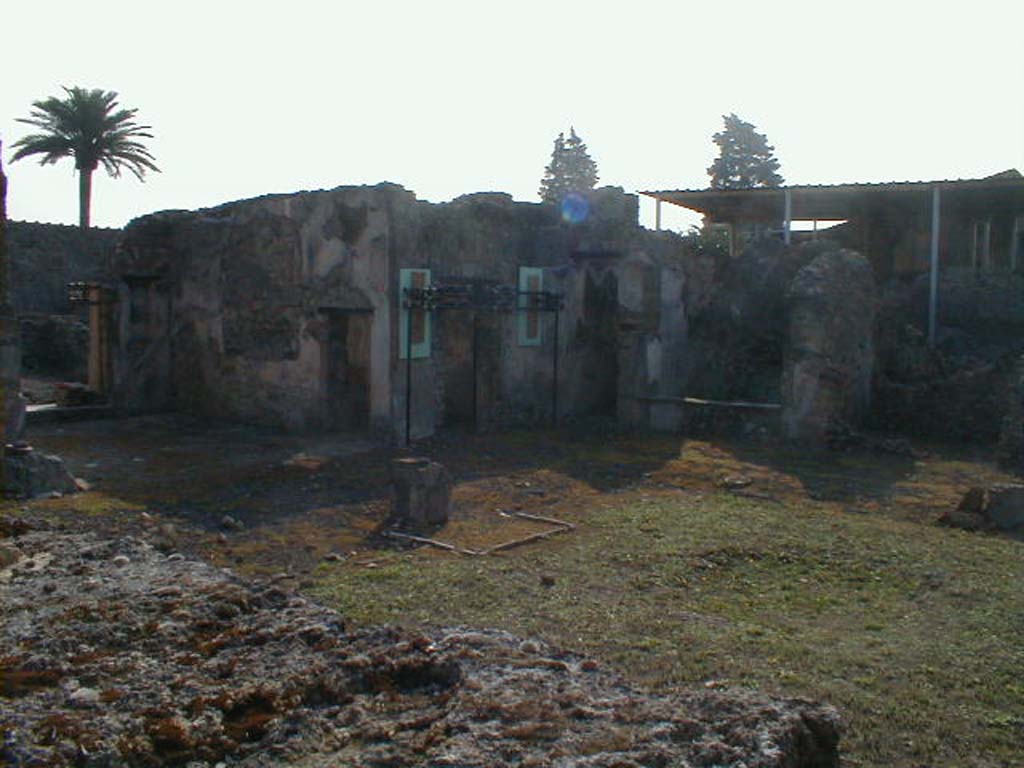 VI.9.5 Pompeii. September 2004. 
South-east side of Corinthian atrium, on the left is the tablinum, in its south wall is a doorway to its neighbouring oecus.
The small entrance on the south side would have led to steps to the upper floor, followed by a small storeroom 25, and then a cubiculum 24, on the right.
