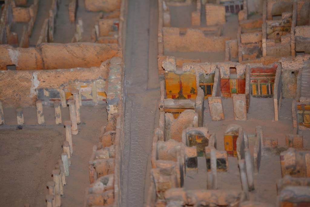 VI.11.9/10 Pompeii. July 2017. Looking west along Vicolo del Mercurio, with VI.12, House of the Faun, on left.
On the right is the south-west corner of atrium 3 (of VI.11.9), with the west wall of the entrance corridor, just visible.
In the corner is the west wall of room 5, with room 4 next to it. 
The doorway to room 6 leads into the room with red/yellow/green west wall, followed by west ala 7. 
Room 8, the area under the stairs, is the undecorated area next to it. 
From cork model in Naples Archaeological Museum.
Foto Annette Haug, ERC Grant 681269 DCOR.
