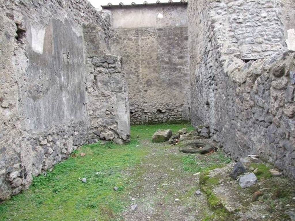 VI.16.5 Pompeii. December 2007. Looking west across shop towards rear room. According to Sogliano in NdS, when first excavated the walls were unadorned.  Leaning against the right of the north wall were the remains of a large masonry feature with two steps before it.
To the right of this same and really in the north-east corner, there seemed to be seen the remains of a fusorium. Towards the other side of the same wall, there was a circular lava cistern mouth, (centre right of photo). See Notizie degli Scav idi Antichità, 1906, (p.350, and plan on p.346).
