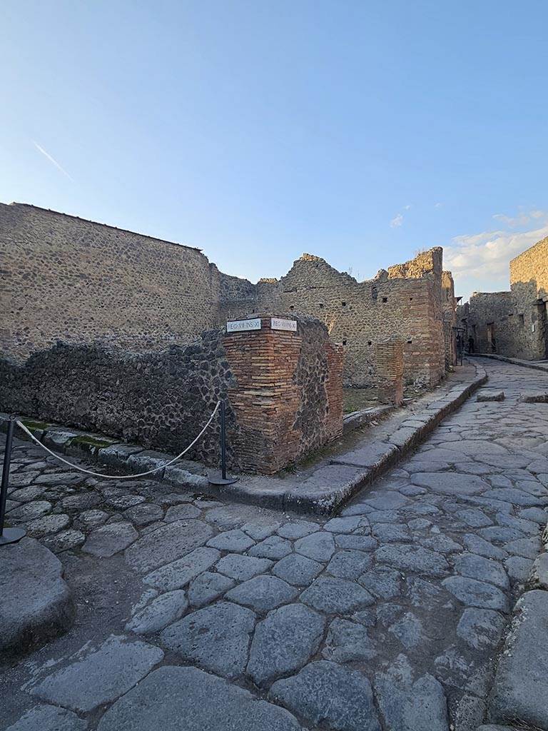 VII.11.17 and 16 Pompeii. November 2024. 
Looking north from junction towards entrance doorways on Vicolo del Lupanare, in centre.
Vicolo degli Scheletri is on the left. Photo courtesy of Annette Haug.
