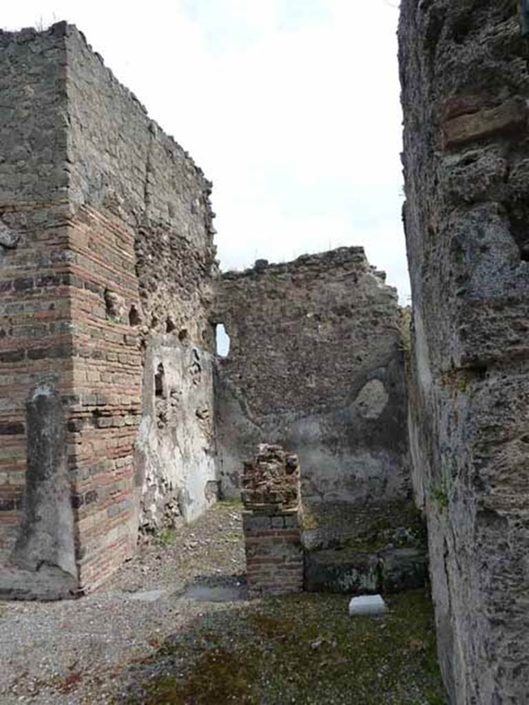 VII.13.4 Pompeii. May 2010. Looking east from entrance towards steps to upper floor and small storeroom.  According to Fiorelli 
A destra si trova la scaletta del piano superiore attigua ad un rustico cubicolo, che altro ne teneva accanto decorato nelle pareti con bustini rinchiusi in circolo, interamente svaniti,e da figurine isolate in mezzo a scompartimenti architettonici, che si riconoscono tuttavia per quelle di Venere pescatrice, di Paride (?) con Amore sullomero e di Narciso in piedi con Amore allato che si specchia nellonda. Indi evvi lala, che conteneva un grande armadio, e dalla quale entravasi nel cennato cubicolo, nonche in un compreso rustico probabilmente servito per deposito di quel generi, di cui il servo della casa faceva smercio nellannessa bottega.
(trans.To the right, one finds the stairs to the upper floor adjoining to a rustic cubiculum, while another nearby was decorated in the walls with heads enclosed in medallions, entirely faded and vanished, and by isolated figures in the midst of architectural decorations, which one could recognize however, as being Venus Pescatrice, of Paris (?) with Cupid on the shoulder and of Narcissus standing with Cupid who was reflected in the water. 
Then there was the ala, which contained a large cupboard, and from which one entered into the indicated cubiculum, the rustic room probably served for storage of those things which the servant of the house sold in the adjoining shop.)
Fiorelli, G: Descrizione di Pompei, 1875. (p.295-6)
