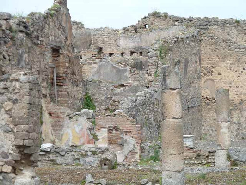 VII.13.4 Pompeii. May 2010.  North-west corner of peristyle with painted plaster, and rear triclinium room of VII.13.21. According to Boyce, on the west wall of the peristyle was a rectangular niche which originally appeared to have been fitted with an aedicula faade but now gone. The interior walls were coated with white stucco and had delicate decorations in relief, including a cornice which ran around the top of the three walls.
See Boyce G. K., 1937. Corpus of the Lararia of Pompeii. Rome: MAAR 14.  (p.71 no.323)
