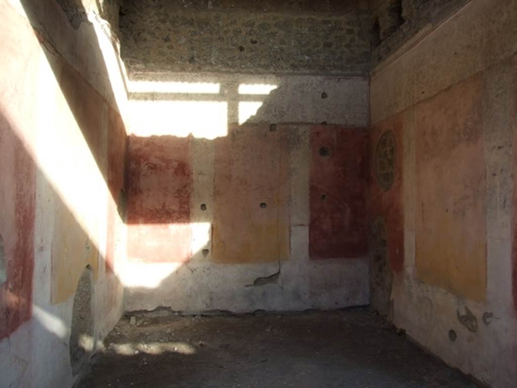 IX.5.11 Pompeii. December 2007. Room 3, looking east. The ala was decorated with red and yellow panels, in half of which were painted Cupids. Under the panels was a black zoccolo, and above them was a frieze finishing above with a stucco cornice. In the small panels of this frieze we see painted on the back (east) wall, a womans figure on foot, crowned with fronds and dressed in a green robe, holding a plate or basket in her left hand, and holding the lower edge of her robe with her right hand. On the wall to the right, was a Cupid with club, and under in small rectangles with purple backgrounds, one sees two fighters with daggers. On the wall to the left, finally we have another Cupid, that has in his right hand a bunch of grapes and in the left, an object that cannot be defined, below in a rectangle with purple background, one sees an open volume, on which were painted some black words, in part vanished and difficult to read. 
See Notizie degli Scavi, 1877, p.248

