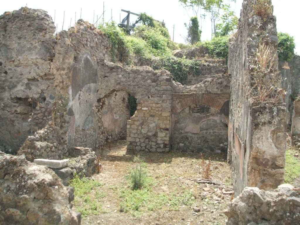 IX.6.7 Pompeii. May 2005. 
Looking south from entrance doorway, into large kitchen (room “p” on plan) with remains of hearth (on left of entrance doorway under the window), a tub/basin against the east wall and doorway to room “s” on east side of peristyle of IX.6.5.
According to Mau, the entrance doorway (at IX.6.7) was originally 2,11m wide so he assumed that here, at one time, some industry was done, but that it was later narrowed to 1.06m.  In the last times of the house - 
Room "p" was the kitchen with hearth leaning against the north wall, and above it was a square window. Against the east wall, a tub/basin was leaning (2.24 x 0.76 measured externally, and 0,65 high) with a hole near the bottom, which, however, was completely filled with various stones added with mortar. 
Room "q" was the latrine with small window that narrowed towards the vicolo. 
Rooms "r" and "s" could be considered as cupboards/storerooms and each had a window into the kitchen, which for its part had a small window near to the south-west corner onto the peristyle, and in the same corner a niche (0.40 high x 0.33 wide) that could have been used as a lararium or for putting a light, or for the figurines of the Lares: a lararium painting was not found.
See Mau in Bullettino dell’Instituto di Corrispondenza Archeologica (DAIR), 1880, (p.231)

According to Della Corte, the following electoral recommendation was found here -

Oppius (Gratus) rog(at)      [CIL IV 3696]  

See Della Corte, M., 1965. Case ed Abitanti di Pompei. Napoli: Fausto Fiorentino.(p.164, note 3)

According to Epigraphik-Datenbank Clauss/Slaby (See www.manfredclauss.de), this read as –

Oppiu<m=S> Severum aed(ilem)      [CIL IV 3696]
