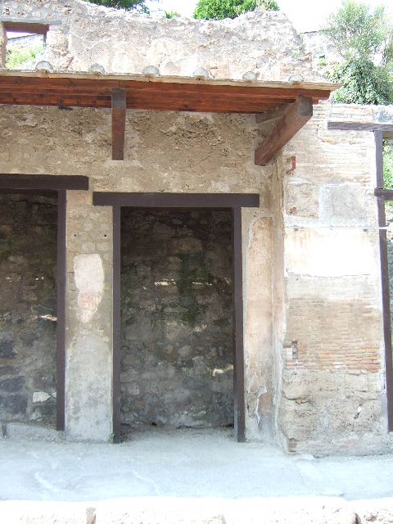 IX.7.5 Pompeii. May 2006. Entrance to workshop. The felt workers or coactiliarii produced cloth by rubbing and pressing hare pelts or “dead” wool. The cloth was treated with coagulants made using boiled vinegar. 
Their work is depicted in a painting at the entrance to the workshop of Verecundus on Via dell’Abbondanza, which also made rather costly clothing.  A graffito found there mentions a tunica lintea aurata, (CIL IV 9083). This was a garment made of linen with inserts made of spun gold. See Panetta, M.R. (2004). Pompeii, the history,life and art of the buried city. Italy, White Star Publishers, (p.169)
