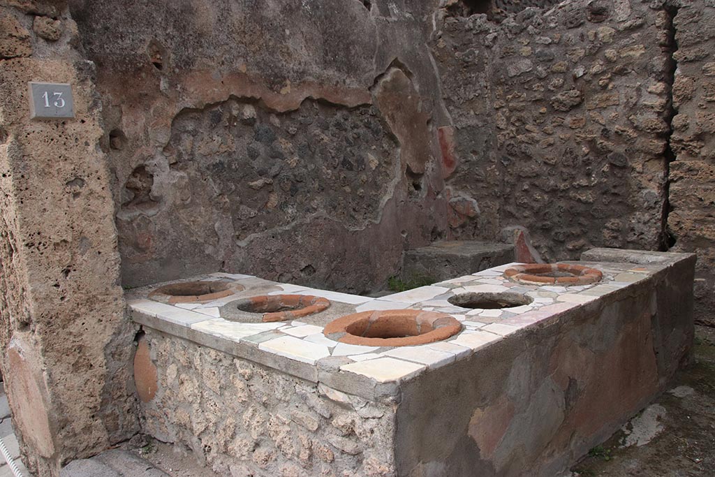 IX.7.13 Pompeii. October 2024. Looking north-west across podium/counter with inset dolia. Photo courtesy of Klaus Heese.