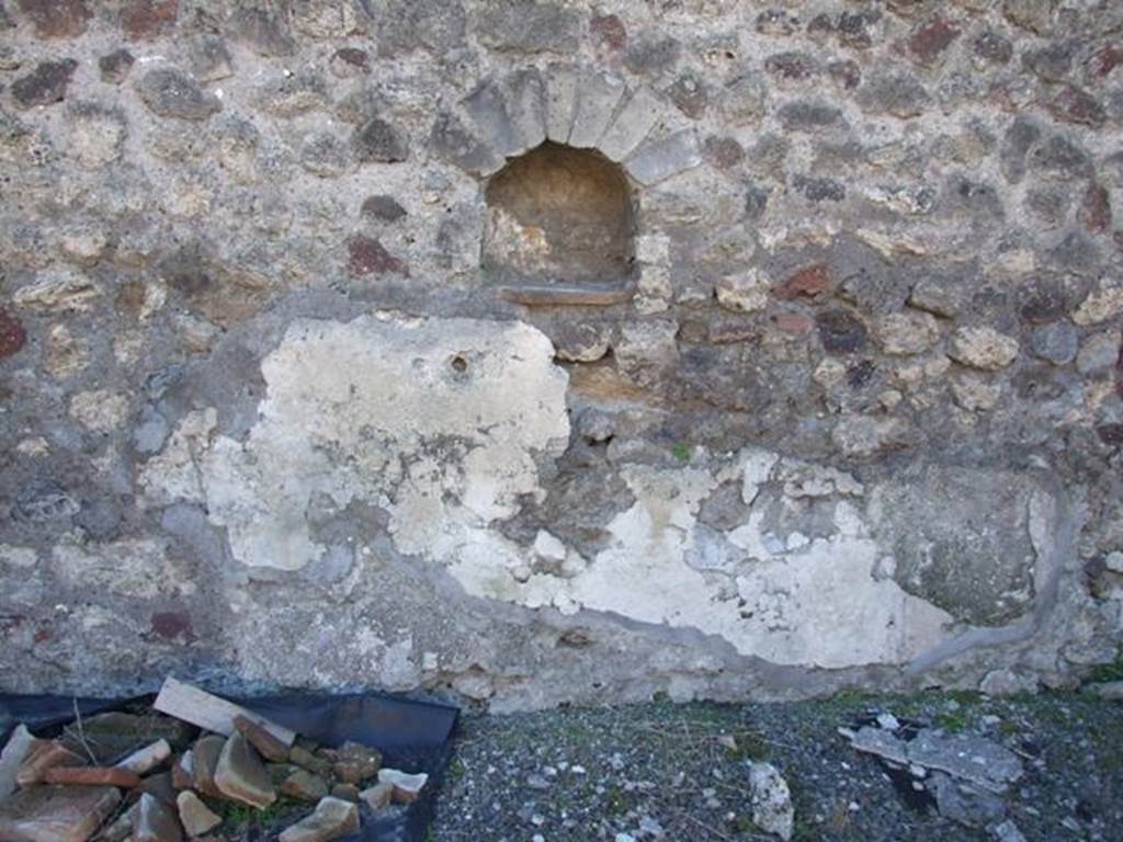 IX.9.a Pompeii. March 2009. Arched niche in west wall, with lararium painting below. According to NdS, the only decoration that remained from the peristyle walls was the lararium painting on the west wall, under the small niche. Here the Genius could be seen sacrificing at an altar, a serpent wrapped around the altar, from the right could be seen a Camillus carrying ribbons and a plate, with a knife for sacrificing the pig. The pig was decorated with a large band around its belly.  See Notizie degli Scavi, 1888, p. 515.
