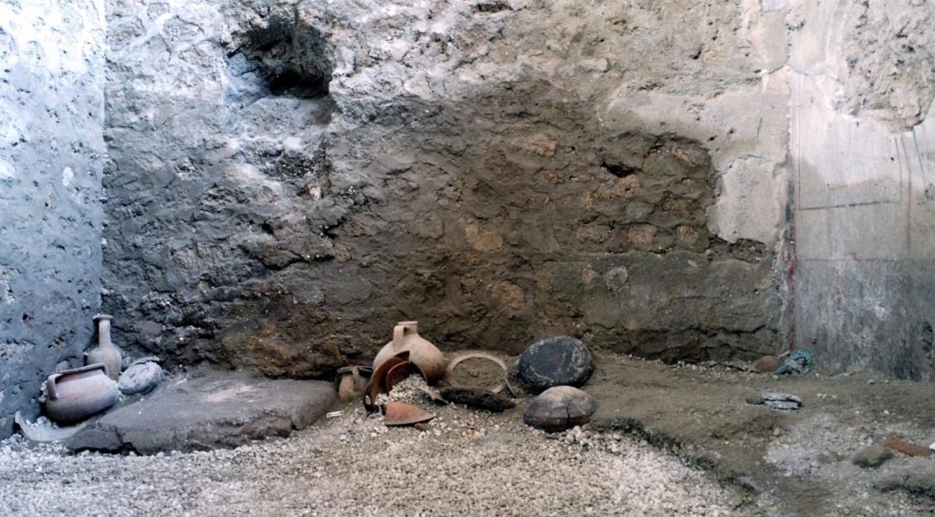 IX.12.B/IX.12.9 Pompeii. May 2023. Room “a”, north end of room with remains of vessels, bowls and jugs stacked against the wall.
Estremità nord della stanza con resti di vasi, ciotole e brocche accatastate contro la parete di fondo.
Photograph © Parco Archeologico di Pompei.


