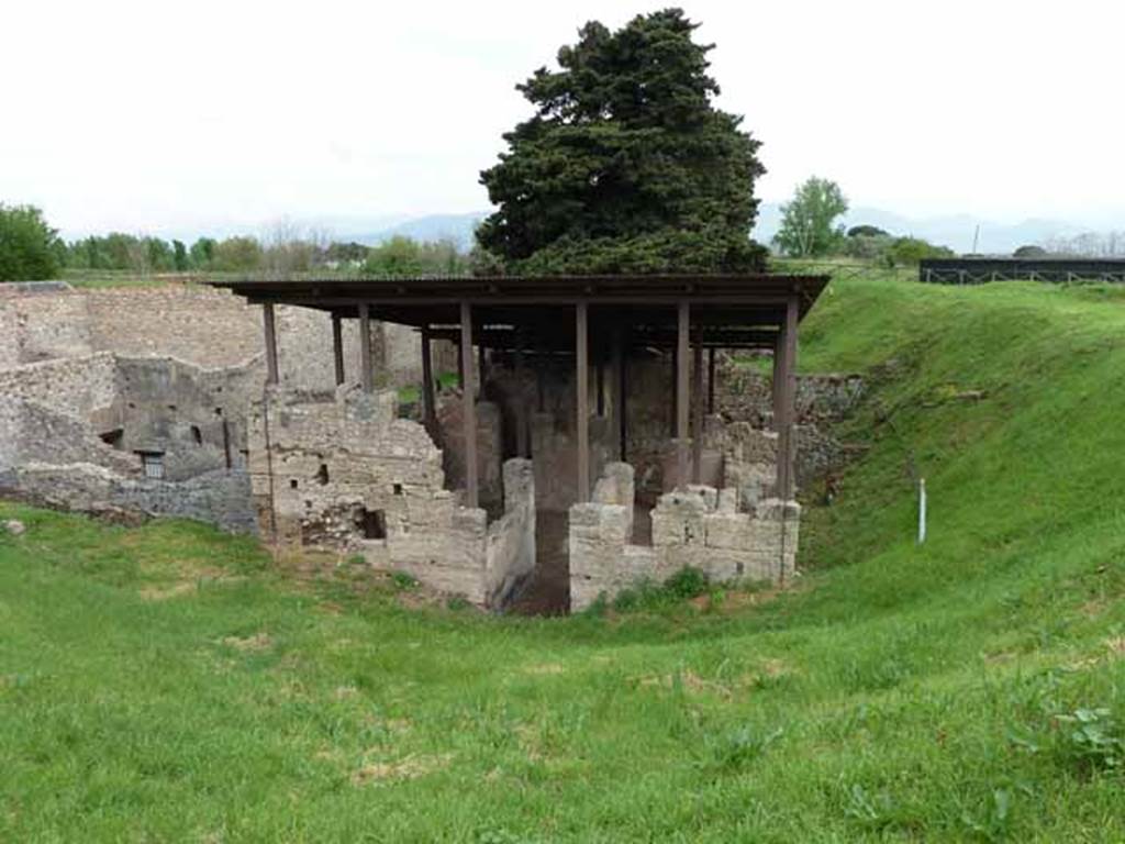 IX.14.c Pompeii. May 2010. Looking east to the front of the house and the entrance. Part of the house is now buried and it would have extended to approximately where the white pole is.