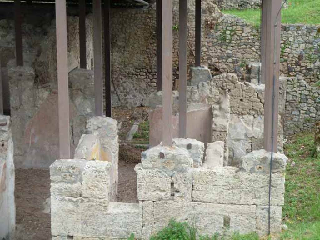 IX.14.c Pompeii. May 2010. Room 5, room to south of fauces 1. This room had a high level window and a recess for a bed in the south wall. The bed would have stretched along the west wall. Room 7 is on the right with room 8 at the far right end. Centre rear can be seen the gutter in garden 3. On the north side of the garden must have been a roof, as proved by a gutter in cocciopesto, shown on the plan with a dotted line. The garden was of rectangular shape, its walls whilst rough, were covered in white plaster. There was an earthenware circular puteal (c), near the area numbered 9. On the left of the west wall of the garden was a well-preserved masonry staircase, (d), which led to the upper floor.
See Notizie degli Scavi, 1911, (p.375).