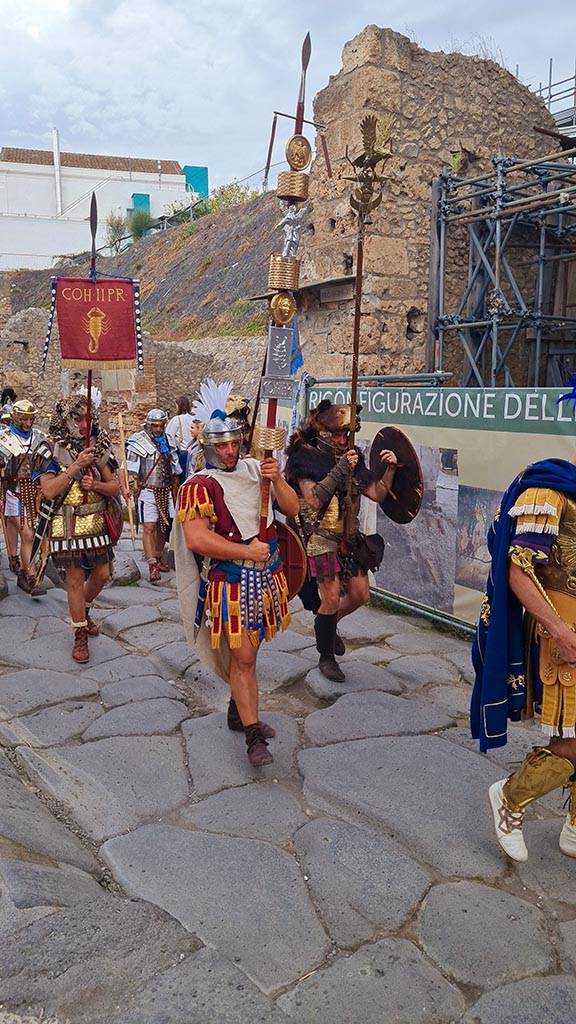 Via dell’Abbondanza, north side. 28th September 2024. 
Roman Legionaries carrying the standard of COH II PR (The second Praetorian Cohort).
Looking west towards IX.11 end of insula wall, and unnamed vicolo between IX.11 and IX.12, during “Ludi Pompeiani” event. 
Photo courtesy of Giuseppe Ciaramella.

