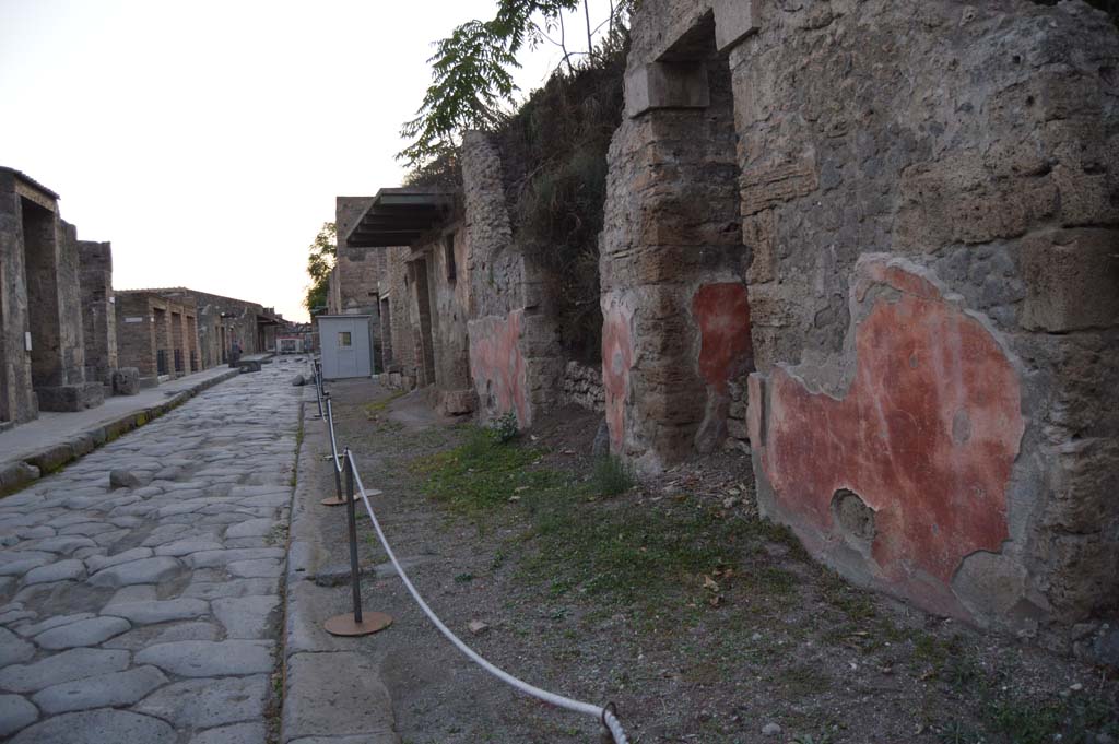 Via dell’Abbondanza, north side. December 2004. III.5.4 on left under bushes, III.5.5 on west corner of junction with unnamed vicolo. 