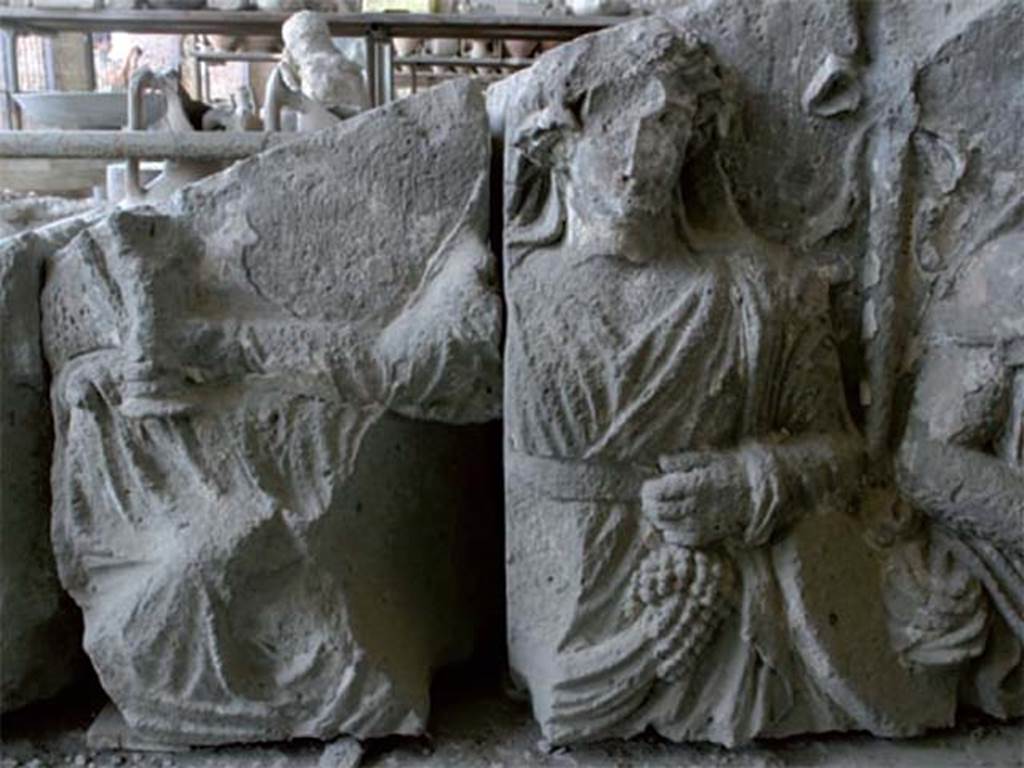 Tempio dionisiaco in località Sant’Abbondio di Pompei. December 2005. Pediment from front of temple, stored in Pompeii Forum Granary Store VII.7.29. Detail of Dionysus with arm outstretched, holding a cup in his right hand and grapes in his left hand.