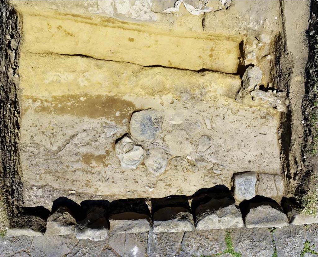 Fig. 10 – Zenithal view of the paved road intercepted between the portico and via dei Sepolcri in front of the N20a fountain.
Photo: B. Lemaire-EFR.
In front of the fountain, a paved path whose axis diverges appreciably from the current via dei Sepolcri, was found about 0.40 m below the level of the embankment which, from the current path, rises slightly to the level circulation of the gantry (fig. 10). It is quite probable that this road, whose pavement clearly bears the marks of recharging and repairs, is to be related to a segment of paved road discovered a few metres further upstream, in front of the HGE14 shop (fig. 11). The two segments are paved with basalt slabs of dimensions appreciably smaller than those of the way in use in 79.

Fig. 10 – Vue zénithale de la voie dallée interceptée entre le portique et la via dei Sepolcri devant la fontaine N20a.
Cliché : B. Lemaire-EFR.
Devant la fontaine, une voie dallée dont l’axe diverge sensiblement de l’actuelle via dei Sepolcri, a été retrouvée à environ 0,40 m sous le niveau du talus qui, depuis la voie actuelle, monte en légère pente jusqu’au niveau de circulation du portique (fig. 10). Il est assez probable que cette voie, dont la chaussée porte clairement des marques de recharges et de réfections, soit à mettre en relation avec un segment de voie dallée découvert quelques mètres plus en amont, devant la boutique HGE14 (fig. 11). Les deux segments sont pavés avec des dalles de basalte de dimensions sensiblement inférieures à celles de la voie en usage en 79.

See Pompéi, Porta Ercolano : organisation, gestion et transformations d’une zone suburbaine : Campagne 2016. CEFR 1676
